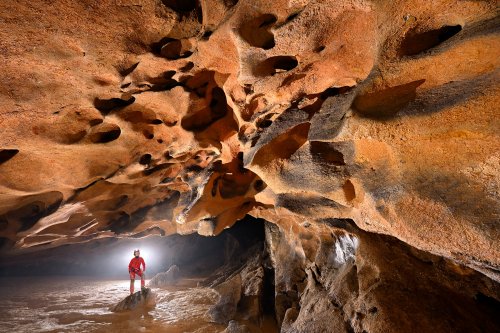 Cueva Fresca (Cantabrie, Espagne) - Galerie au plafond rouge érodé avec personnage en arrière plan dans halo(SP-26-0915)